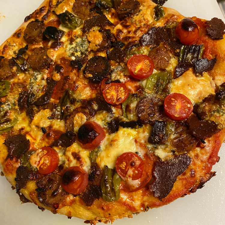 closeup of an uncut pizza with the toppings listed in the caption