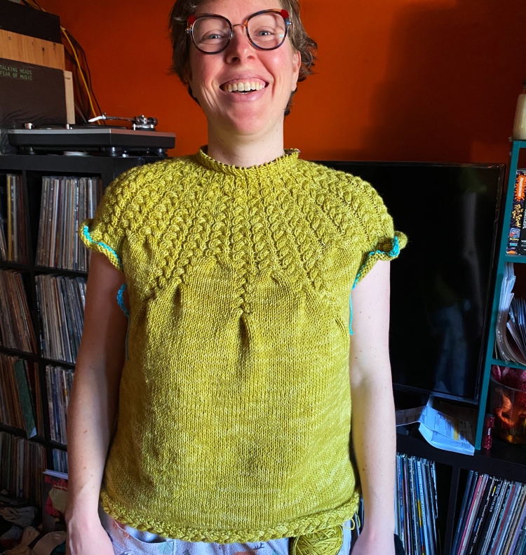 Lee wearing in-progress sweater with yoke completed, crochet-chain provisional stitches where the sleeves will go