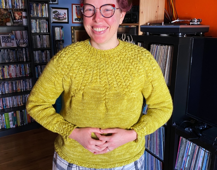 Lee wearing finished sweater, pre-blocking, inside house
