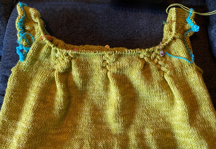 in-progress sweater with a couple of inches of the yoke worked, crochet-chain provisional stitches where the sleeves will go