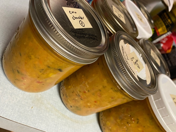 mason jars filled with yellow soup with handwritten labels saying corn chowder with a circled V