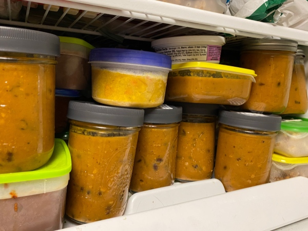 a freezer filled with jars and containers of frozen soups