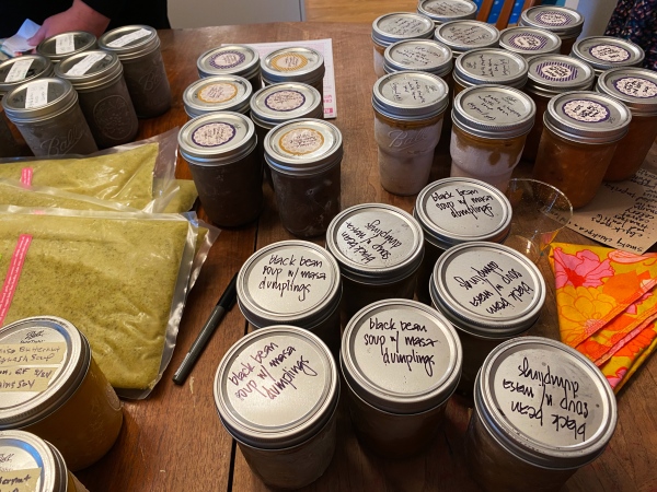 photo of a table filled with glass mason jars of frozen soups, all with labels of some kind