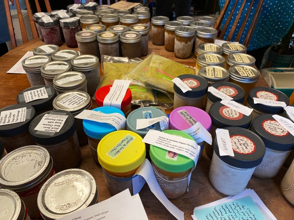 photo of a table filled with glass mason jars of frozen soups, all with labels of some kind